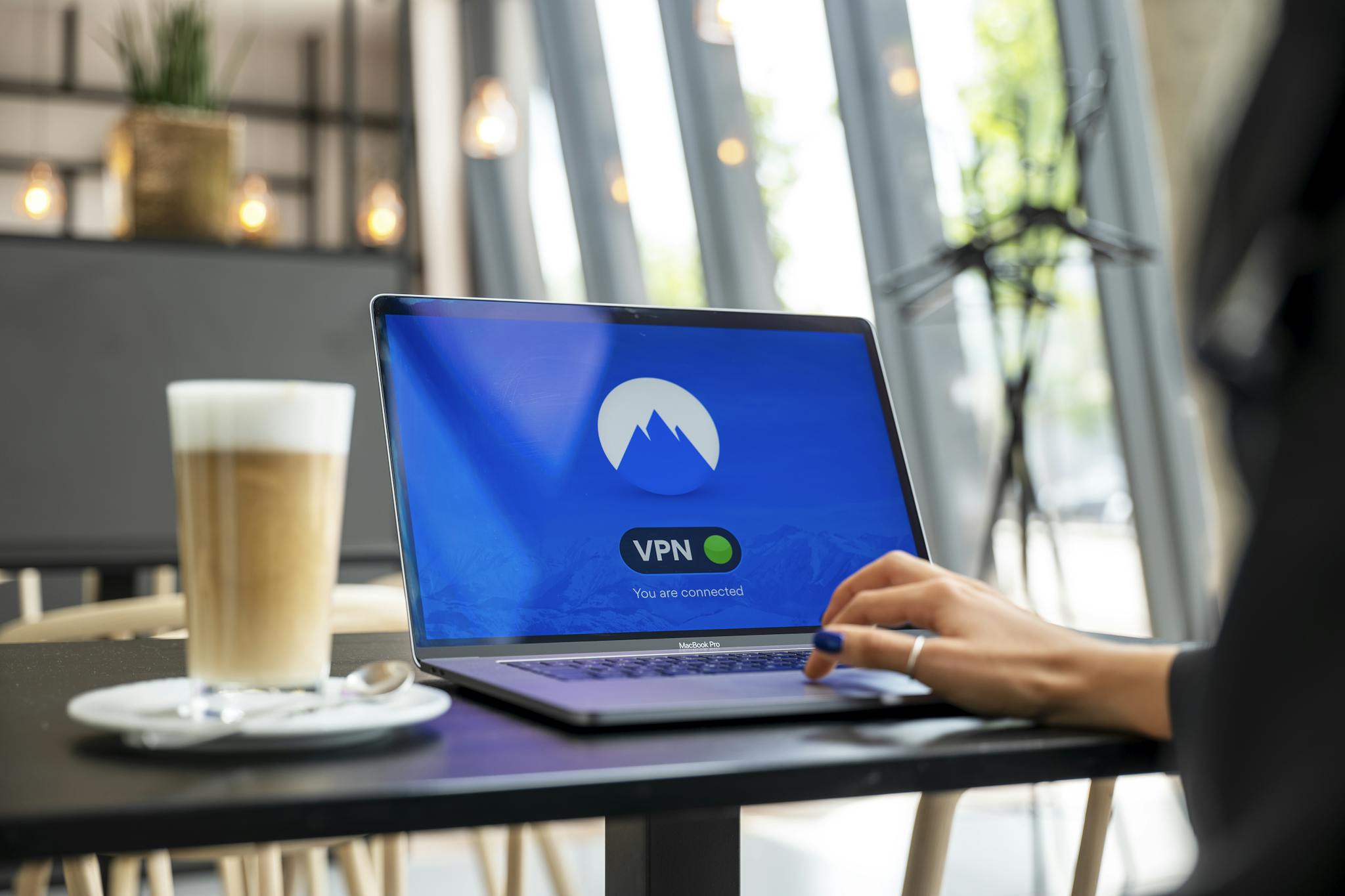 A person using a laptop with a VPN connection in a modern cafe setting, showcasing remote work and internet security.